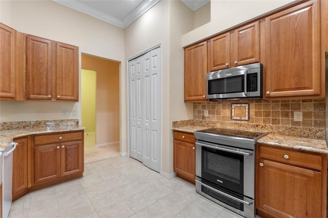 kitchen with appliances with stainless steel finishes, light stone countertops, ornamental molding, and tasteful backsplash