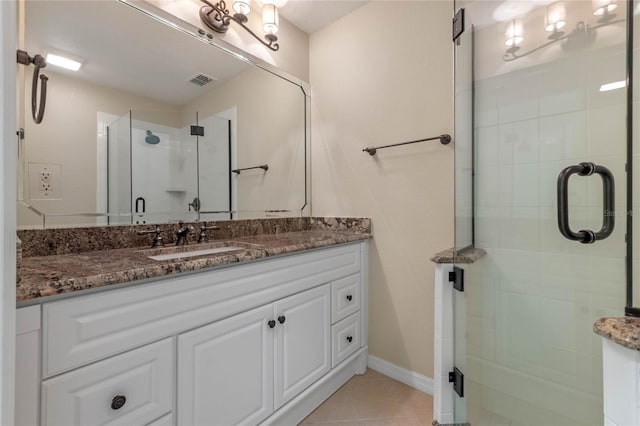 bathroom with a shower with shower door, vanity, and tile patterned floors