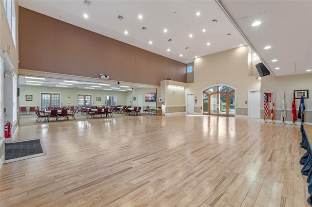 exercise area featuring light hardwood / wood-style floors and a towering ceiling