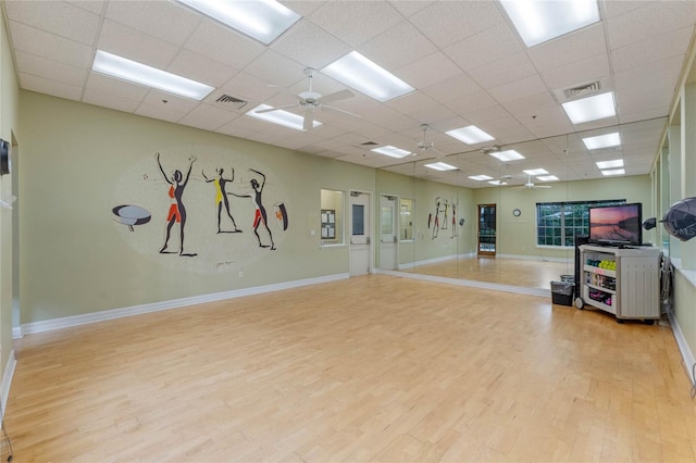 workout area with light hardwood / wood-style flooring, ceiling fan, and a paneled ceiling