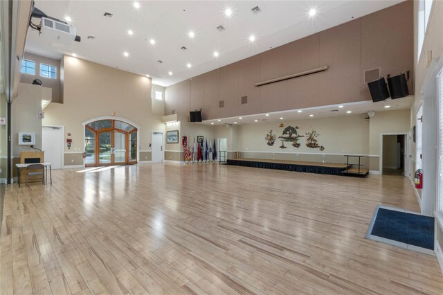 interior space featuring light hardwood / wood-style flooring, french doors, and a towering ceiling