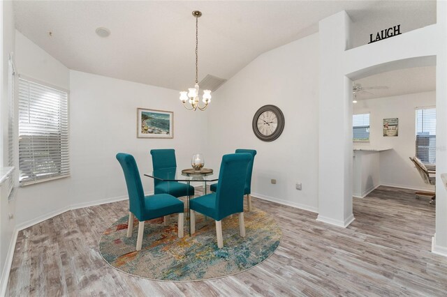 dining space with lofted ceiling, ceiling fan with notable chandelier, and light hardwood / wood-style flooring
