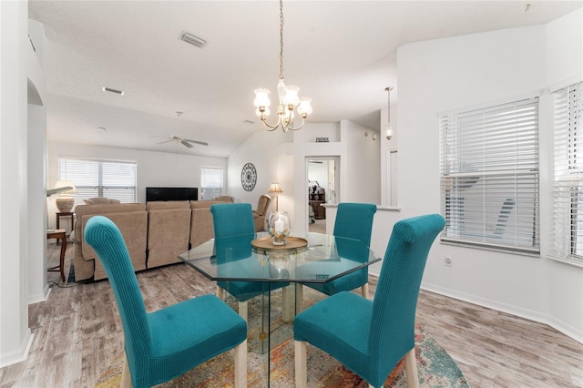 dining space featuring ceiling fan with notable chandelier, lofted ceiling, and light hardwood / wood-style floors