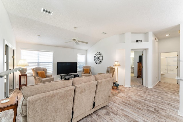 living room featuring ceiling fan, lofted ceiling, a textured ceiling, and light hardwood / wood-style flooring