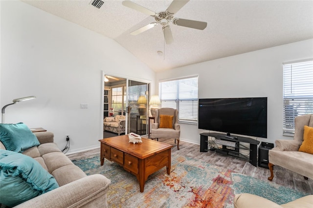 living room featuring light hardwood / wood-style flooring, ceiling fan, vaulted ceiling, and a textured ceiling