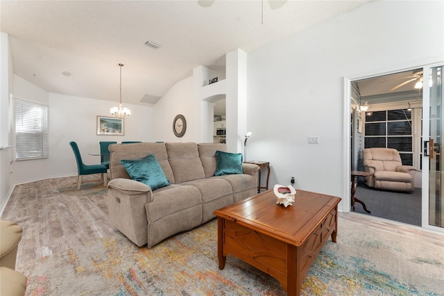 living room featuring ceiling fan with notable chandelier, vaulted ceiling, and light wood-type flooring