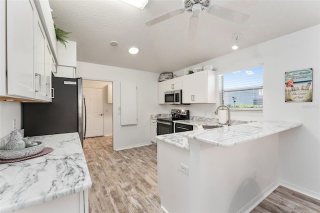 kitchen with sink, white cabinets, kitchen peninsula, stainless steel appliances, and light wood-type flooring