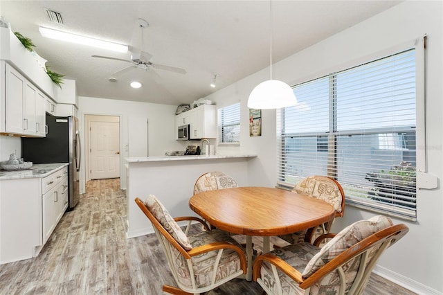 dining area with lofted ceiling, a textured ceiling, light hardwood / wood-style flooring, and ceiling fan