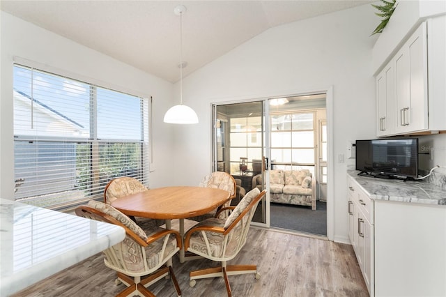 dining area featuring vaulted ceiling and light wood-type flooring