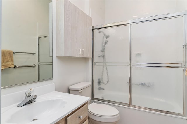 full bathroom featuring vanity, bath / shower combo with glass door, and toilet