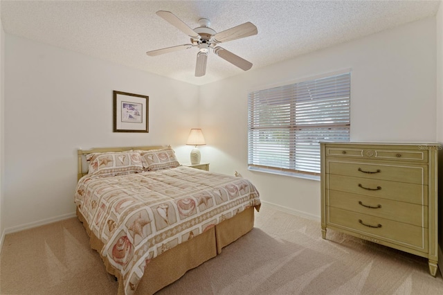 bedroom with light carpet, ceiling fan, and a textured ceiling