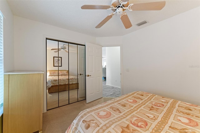 carpeted bedroom with ceiling fan, a closet, and a textured ceiling