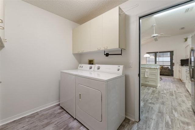 laundry area with light wood-type flooring, cabinets, ceiling fan, washing machine and dryer, and a textured ceiling
