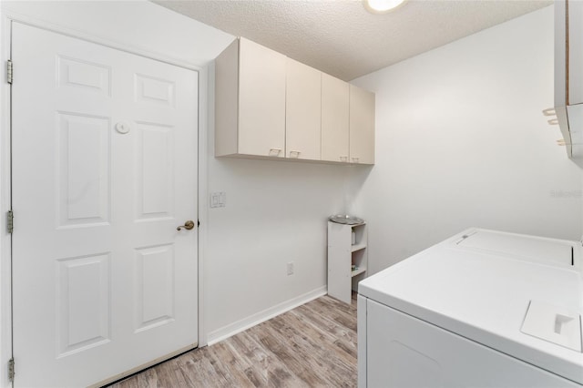 laundry room featuring washer / dryer, light hardwood / wood-style flooring, cabinets, and a textured ceiling