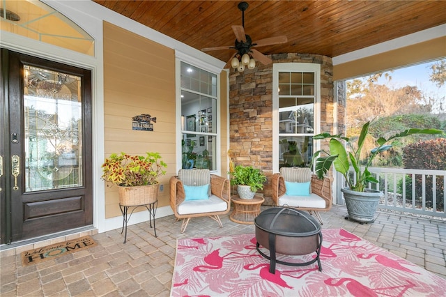 view of patio featuring a porch, ceiling fan, and a fire pit