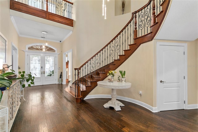 foyer entrance featuring a towering ceiling, hardwood / wood-style flooring, stairs, and baseboards