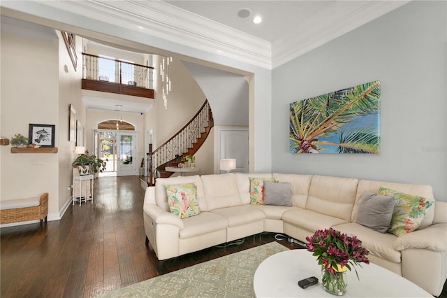 living room with dark wood-style floors, crown molding, stairway, a towering ceiling, and baseboards