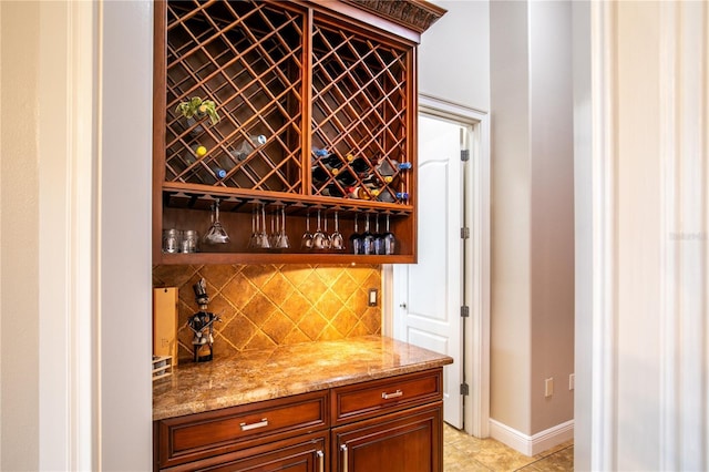 wine room featuring light tile patterned floors, a dry bar, and baseboards