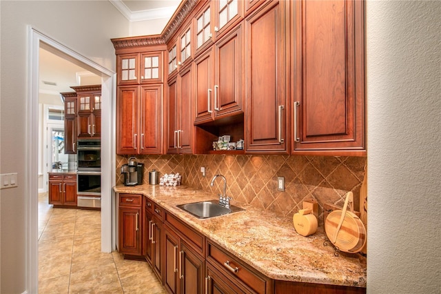 kitchen featuring light tile patterned floors, double oven, a sink, ornamental molding, and backsplash