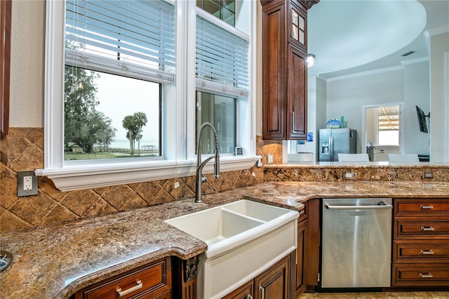 kitchen with stainless steel appliances, stone counters, crown molding, and a sink