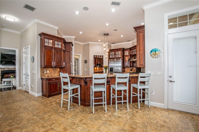 kitchen featuring visible vents, glass insert cabinets, built in refrigerator, a peninsula, and under cabinet range hood