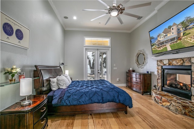 bedroom with ornamental molding, access to exterior, french doors, light wood-type flooring, and a fireplace