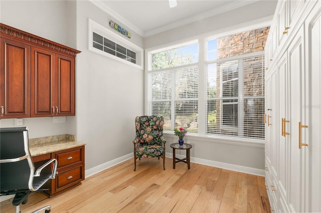 office space with ornamental molding, baseboards, built in desk, and light wood finished floors