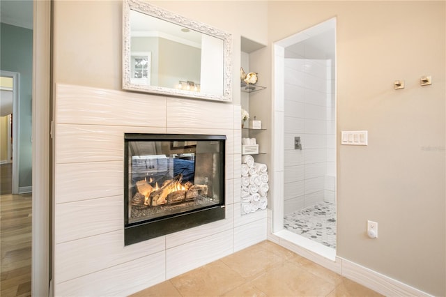 full bathroom with tile patterned flooring, baseboards, tiled shower, and a multi sided fireplace