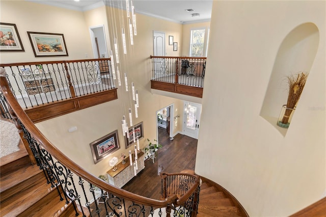 stairway with ornamental molding, wood finished floors, and baseboards