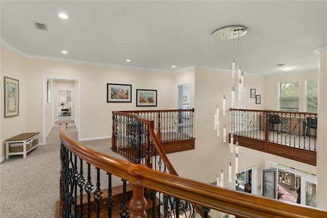 hall with carpet floors, crown molding, visible vents, an upstairs landing, and baseboards