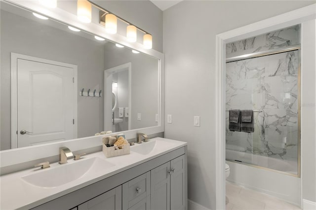 full bathroom with double vanity, bath / shower combo with glass door, toilet, and a sink