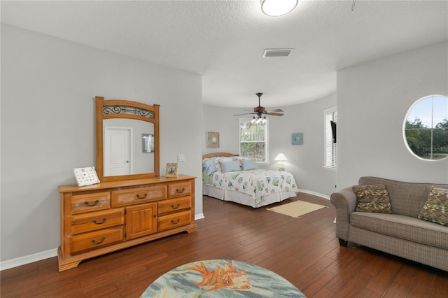 bedroom featuring dark wood-style flooring, visible vents, a ceiling fan, a textured ceiling, and baseboards