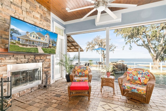 sunroom / solarium featuring a ceiling fan, wooden ceiling, a water view, and an outdoor stone fireplace