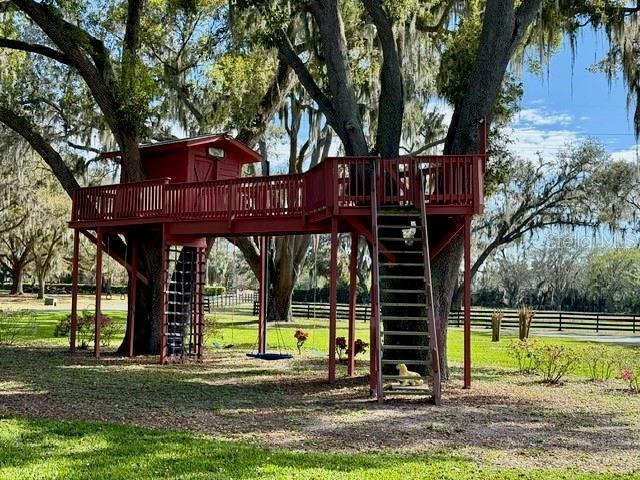 view of play area featuring stairway, fence, and a wooden deck