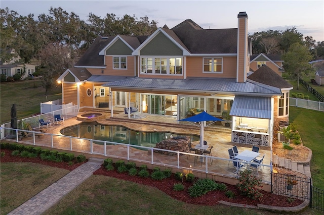 rear view of property with a chimney, a patio area, a fenced backyard, and a lawn