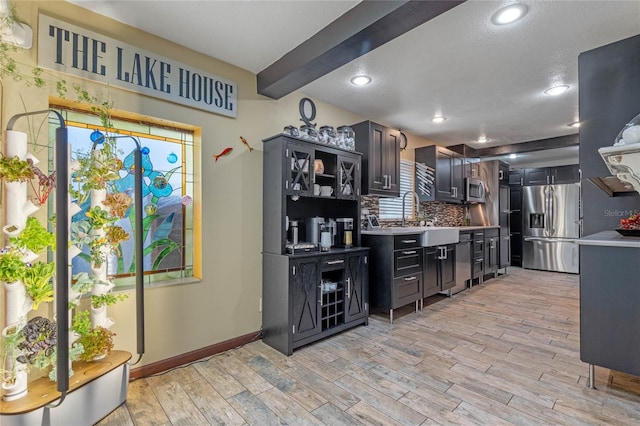 kitchen featuring appliances with stainless steel finishes, sink, backsplash, a textured ceiling, and light hardwood / wood-style flooring