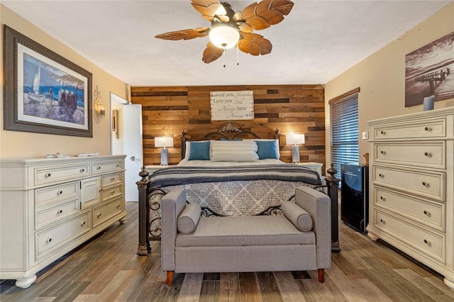 bedroom with ceiling fan, wooden walls, and hardwood / wood-style floors