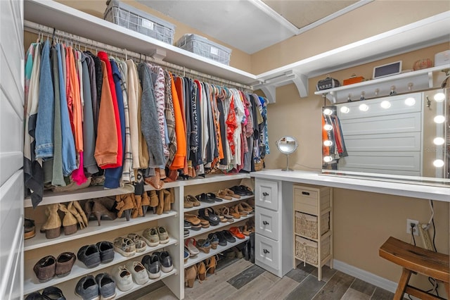 walk in closet with built in desk and hardwood / wood-style floors