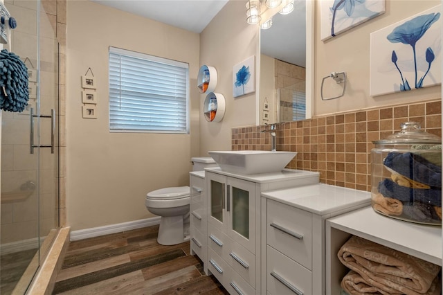 bathroom with hardwood / wood-style floors, tasteful backsplash, vanity, a shower with shower door, and toilet