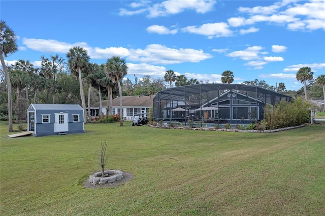 view of yard with a storage shed, a lanai, and an outdoor fire pit