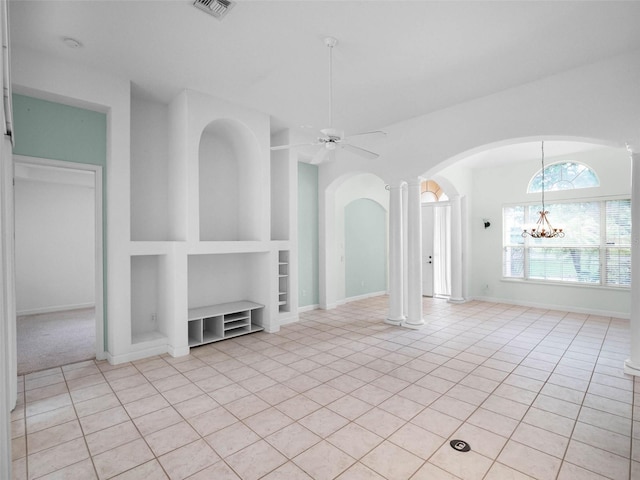 unfurnished living room with built in features, ceiling fan with notable chandelier, decorative columns, arched walkways, and light tile patterned flooring