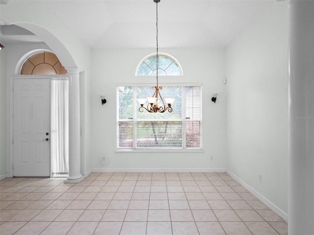 entrance foyer featuring a chandelier, arched walkways, light tile patterned floors, and ornate columns