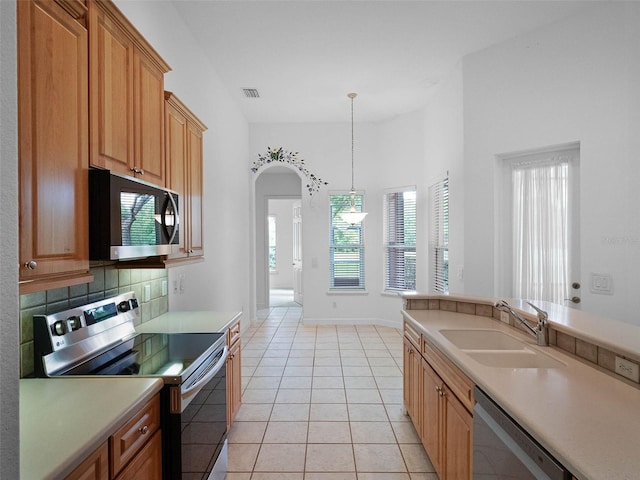 kitchen featuring visible vents, light countertops, a sink, hanging light fixtures, and stainless steel appliances