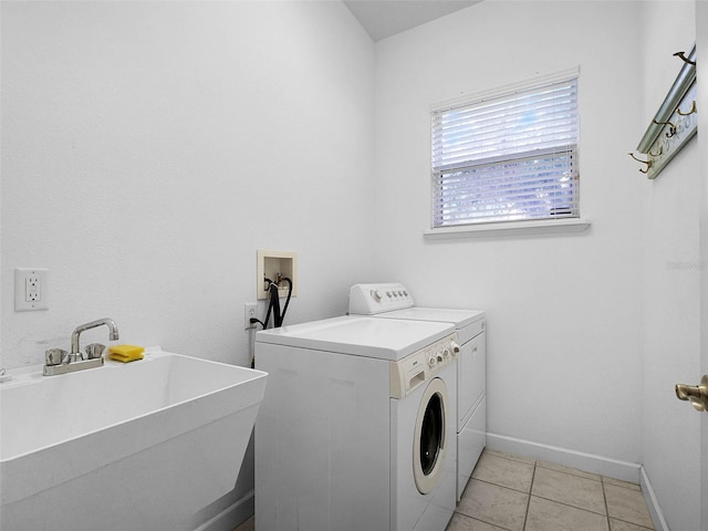 laundry area with laundry area, light tile patterned floors, a sink, baseboards, and washing machine and dryer