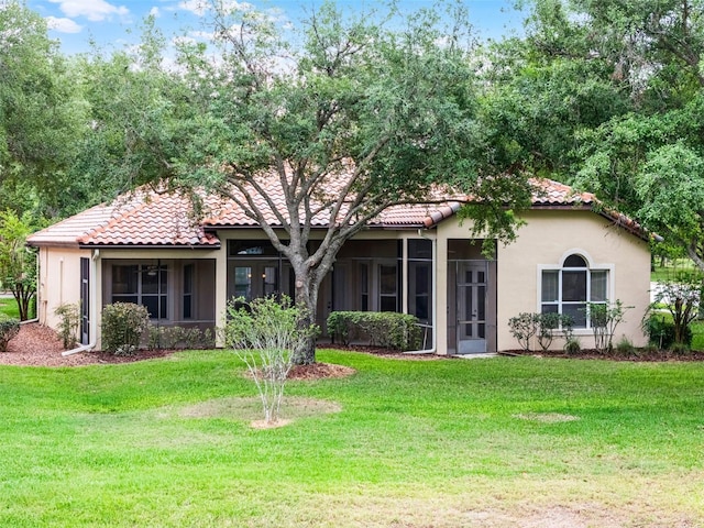 view of front of property featuring a front yard, stucco siding, and a tiled roof