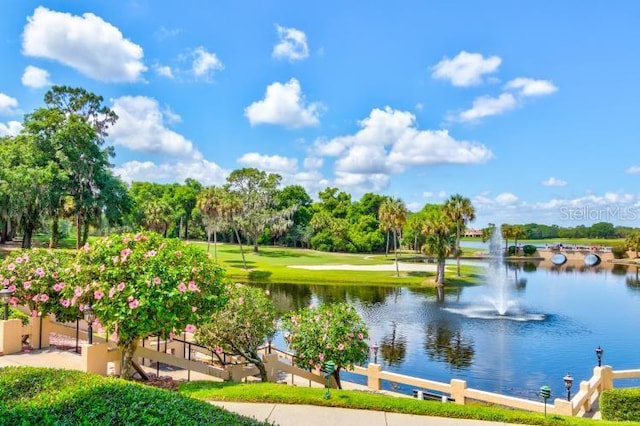 view of home's community with a water view and a lawn