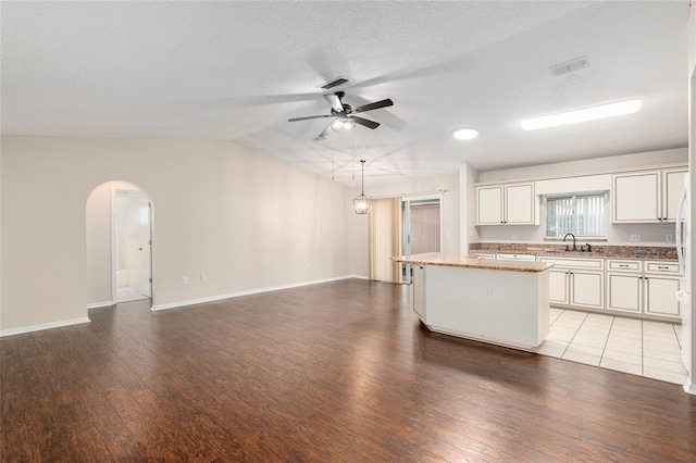 kitchen featuring hardwood / wood-style flooring, a center island, vaulted ceiling, ceiling fan, and pendant lighting