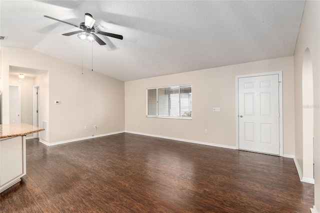 unfurnished living room featuring ceiling fan, vaulted ceiling, dark wood-type flooring, and a textured ceiling