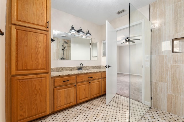 bathroom with a shower, a textured ceiling, ceiling fan, and vanity