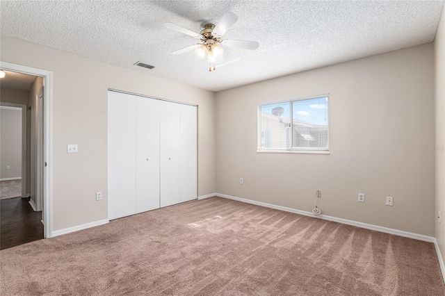 unfurnished bedroom featuring a closet, ceiling fan, carpet flooring, and a textured ceiling